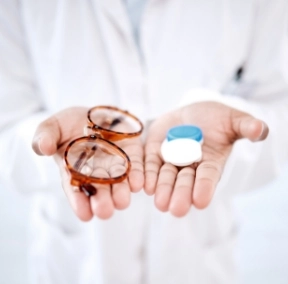 Optometrist holding glasses in one hand and contacts in the other