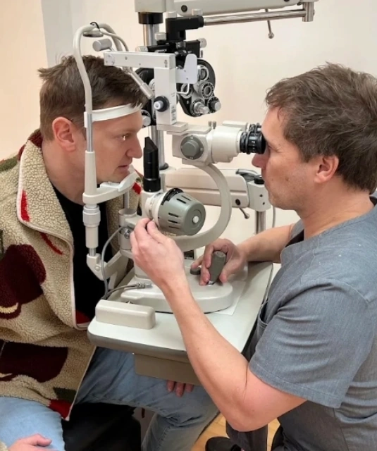Dr. Rex Hamilton examining patient's eye through slit lamp