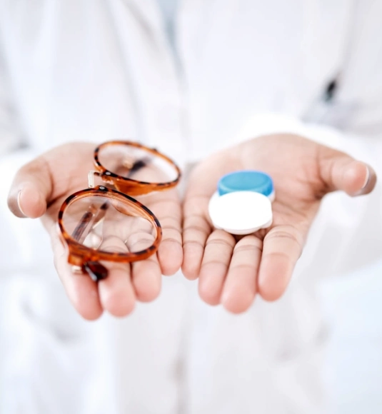 Optometrist holding glasses in one hand and contacts in the other