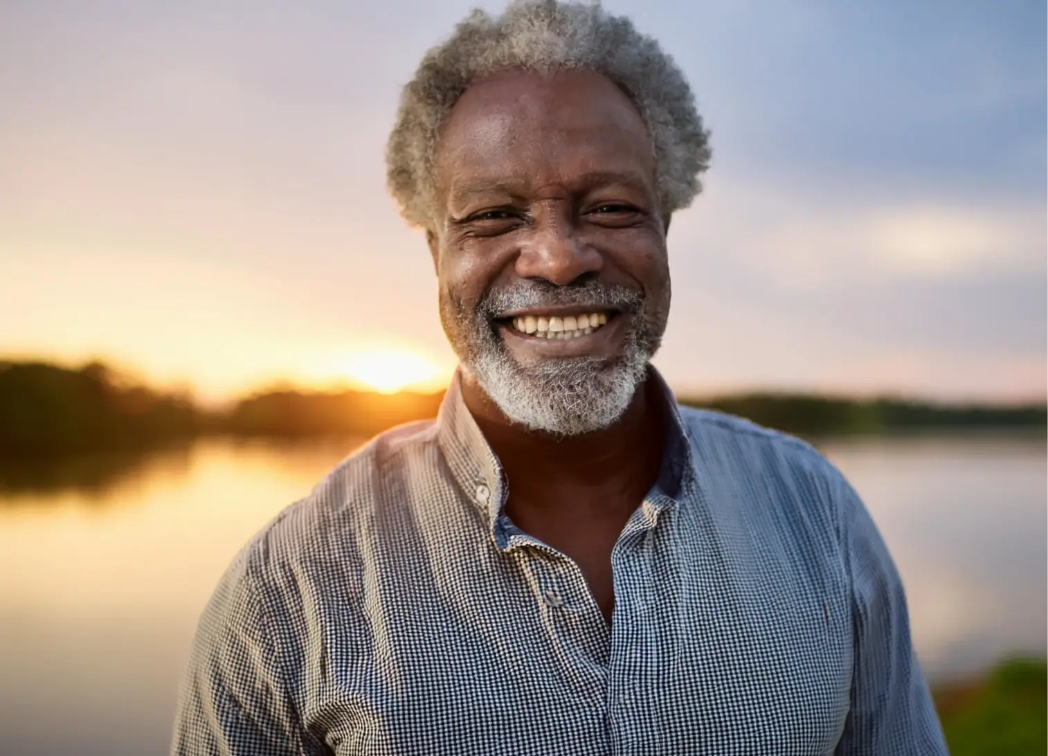elderly man standing by the waterfront at sunset