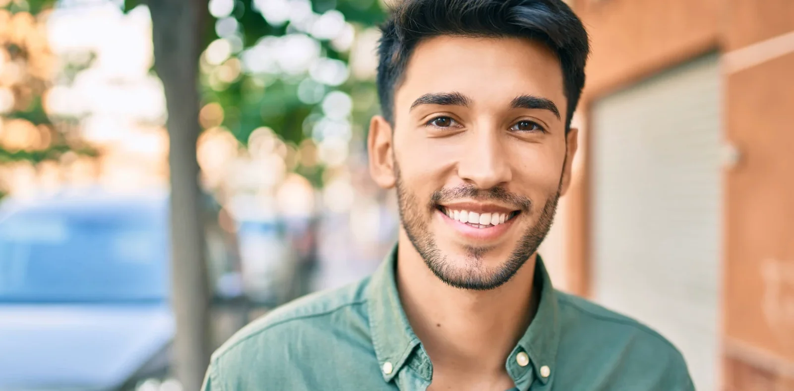 Smiling Hispanic man walking through town after LASIK eye surgery.